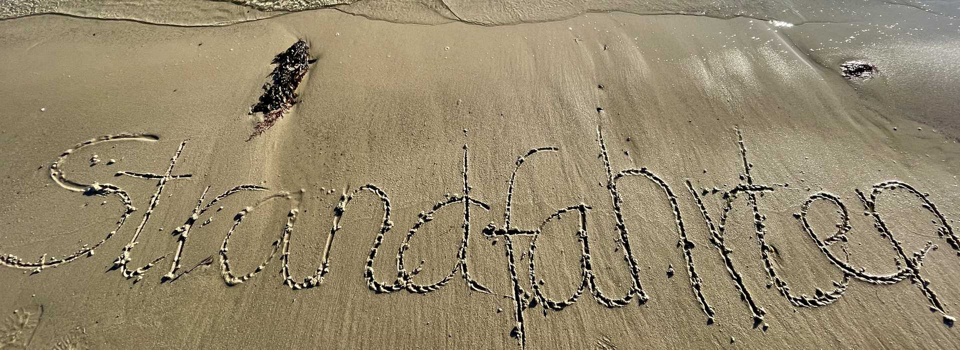 Strandfahrten: Das Bild zeigt einen in den Sand gemahlten Schriftzug "Strandfahrten"
