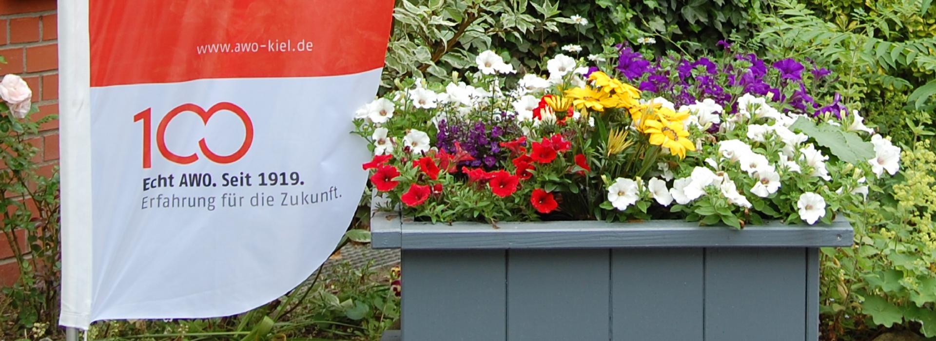AWO Kiel: Das Bild zeigt eine AWO-Fahne mit Blumen.